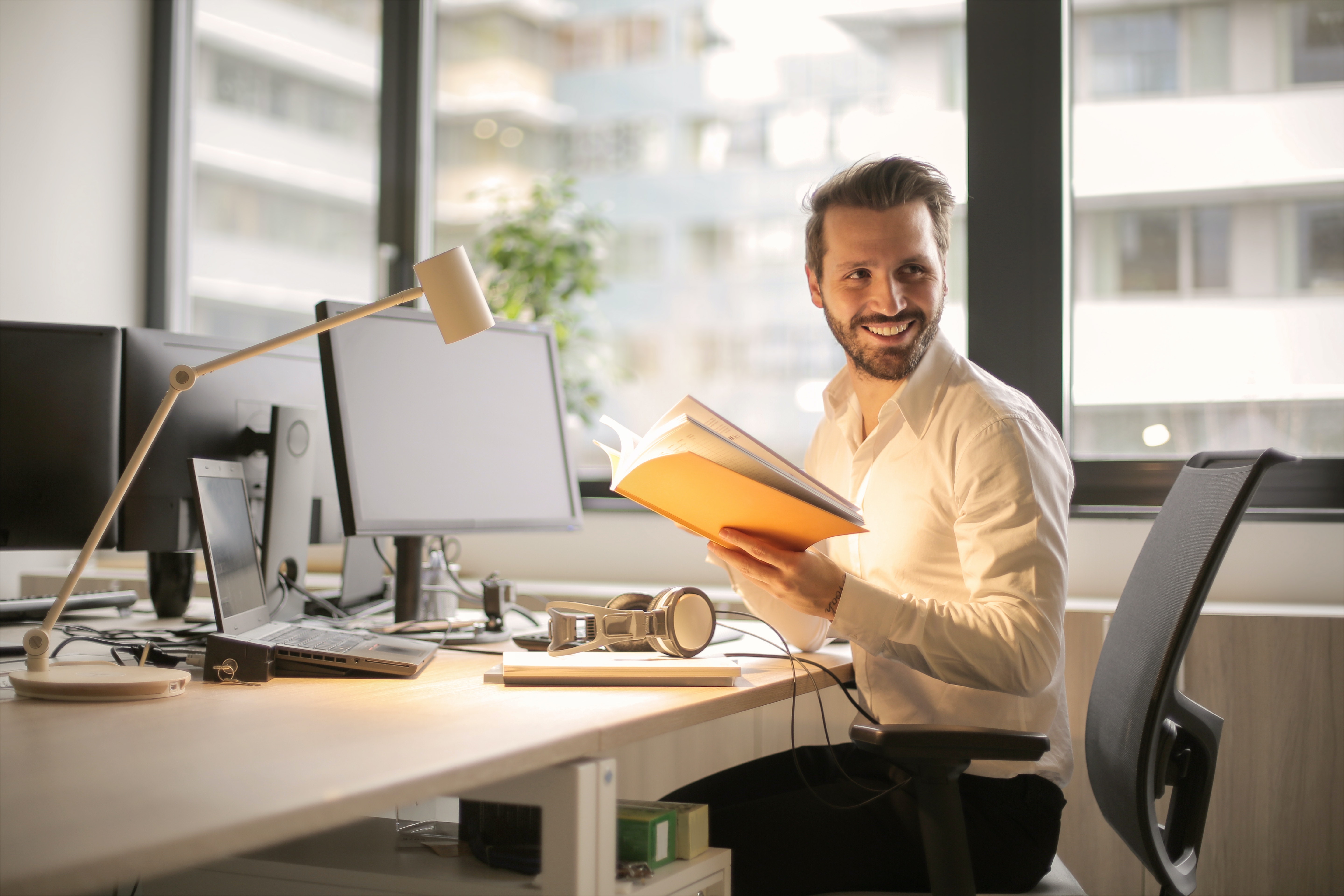 Smiling man at desk holding book